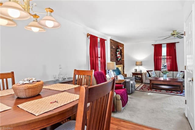 dining area featuring light carpet, light wood-style flooring, and a ceiling fan