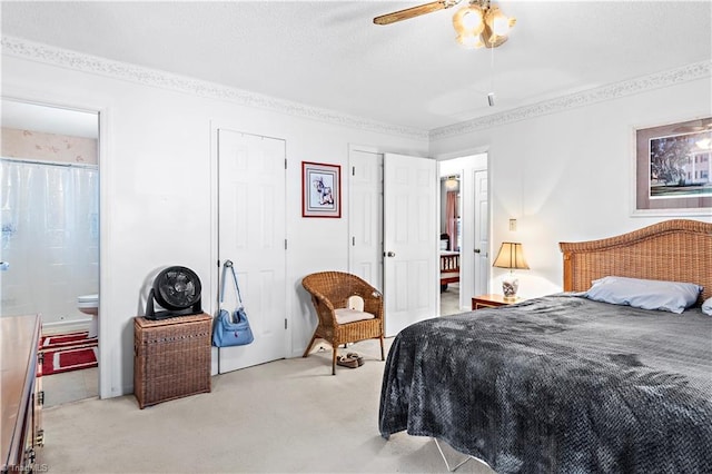 bedroom with light carpet, ceiling fan, ensuite bath, and two closets