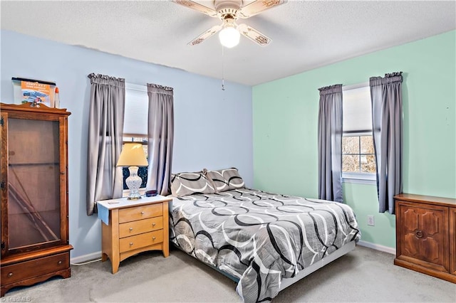 bedroom with light carpet, a textured ceiling, a ceiling fan, and baseboards