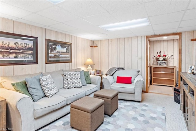 living room featuring wooden walls and a drop ceiling