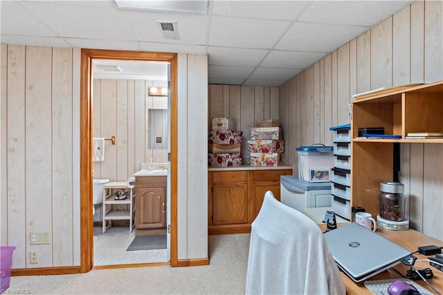 office area with a paneled ceiling, visible vents, and wood walls