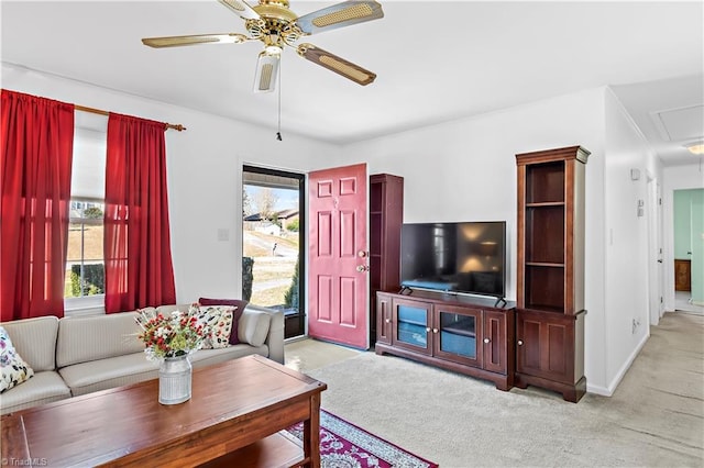 living area with ceiling fan, baseboards, attic access, and light colored carpet