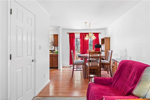 dining space with baseboards, light wood finished floors, and a notable chandelier