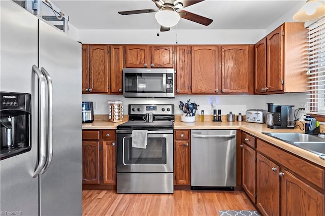 kitchen with appliances with stainless steel finishes, light wood-type flooring, brown cabinetry, and light countertops