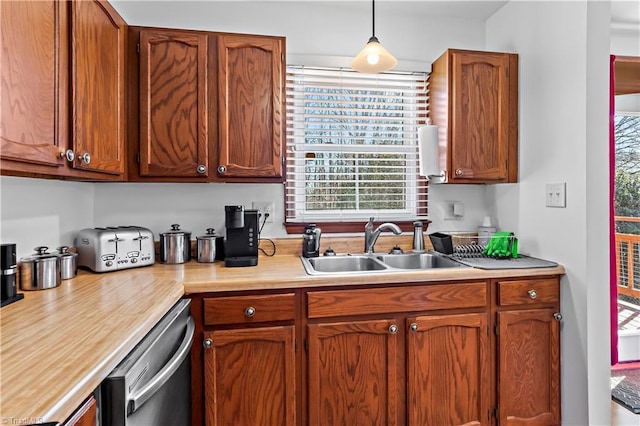 kitchen featuring a sink, light countertops, stainless steel dishwasher, brown cabinets, and pendant lighting