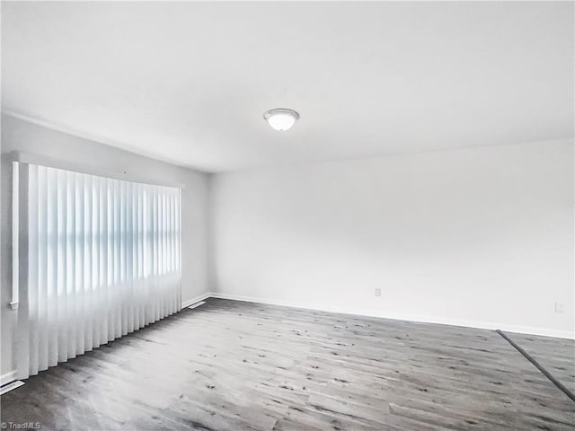 unfurnished room with baseboards and wood finished floors