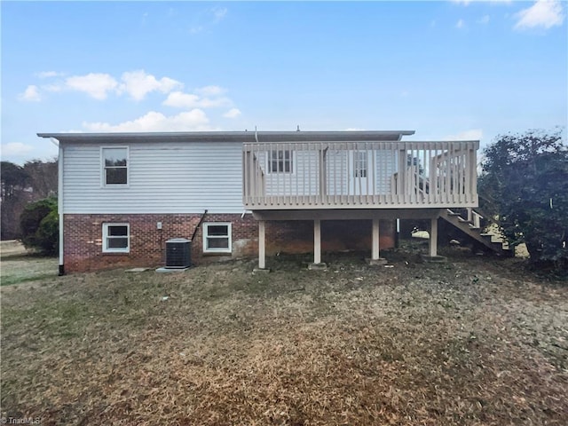 rear view of house featuring brick siding, a lawn, central AC, a wooden deck, and stairs