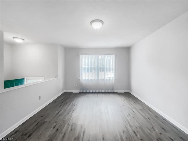 spare room with baseboards and wood finished floors