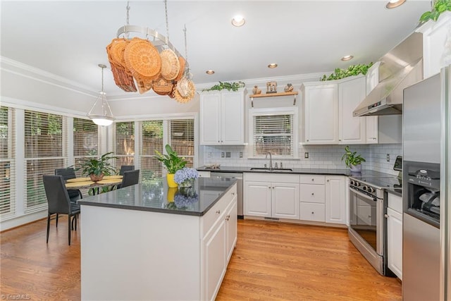 4002 Hobbs Rd, Greensboro, NC 27410 - kitchen with appliances with stainless steel finishes, white cabinetry, tasteful backsplash, a kitchen island, and light wood-style flooring