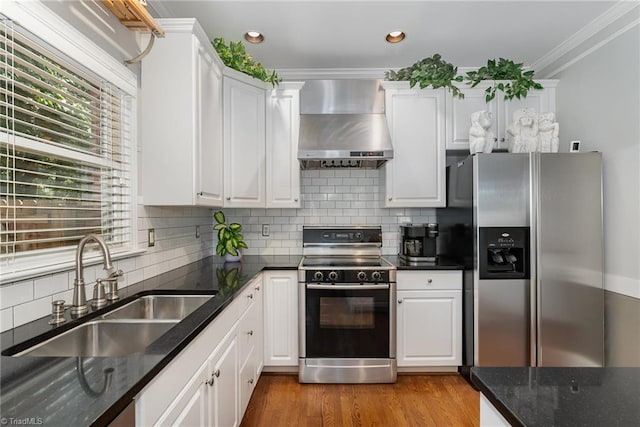4002 Hobbs Rd, Greensboro, NC 27410 - kitchen featuring wall chimney range hood, stainless steel appliances, crown molding, white cabinetry, and decorative backsplash