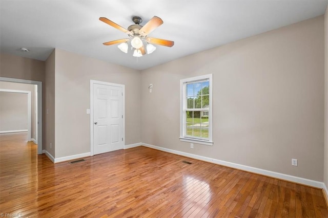 spare room with baseboards, light wood-type flooring, visible vents, and a ceiling fan