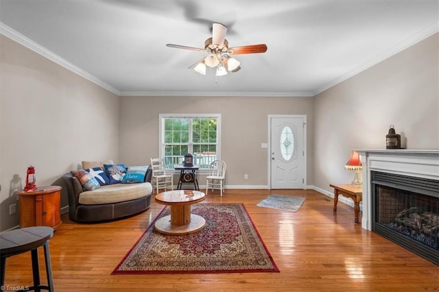 living area with wood finished floors, a ceiling fan, and crown molding