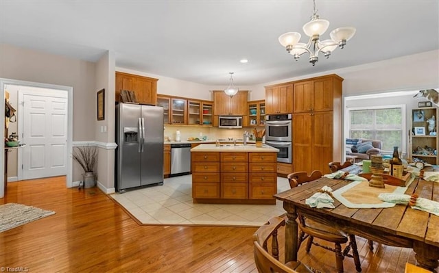kitchen with appliances with stainless steel finishes, light wood-style floors, a chandelier, light countertops, and brown cabinetry