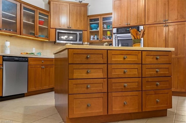 kitchen featuring light tile patterned floors, brown cabinets, stainless steel appliances, and tasteful backsplash