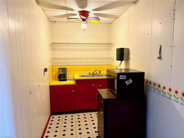 kitchen with ceiling fan, sink, and wood walls