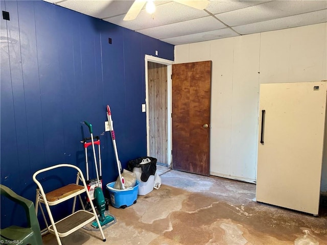 misc room featuring concrete flooring, ceiling fan, and wooden walls