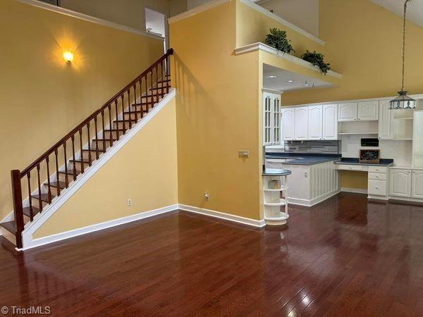 kitchen with baseboards, dark wood-style flooring, a high ceiling, white cabinetry, and open shelves