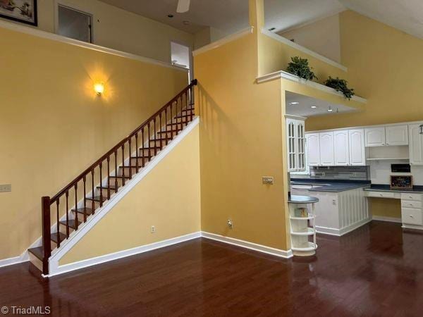 kitchen featuring baseboards, dark wood finished floors, a high ceiling, white cabinets, and dark countertops