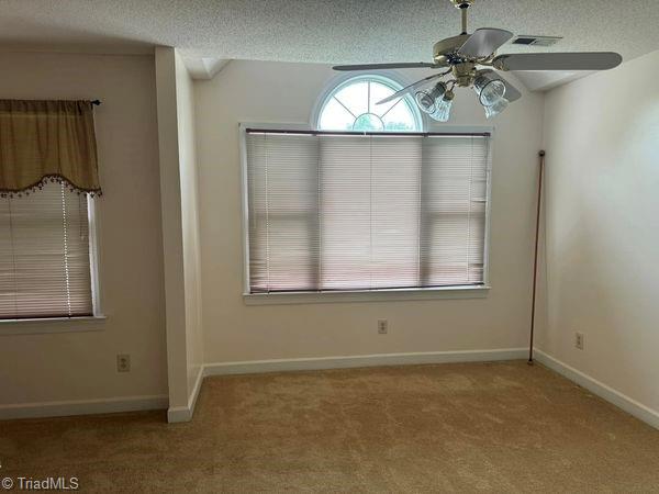 empty room with baseboards, carpet, a ceiling fan, and a textured ceiling