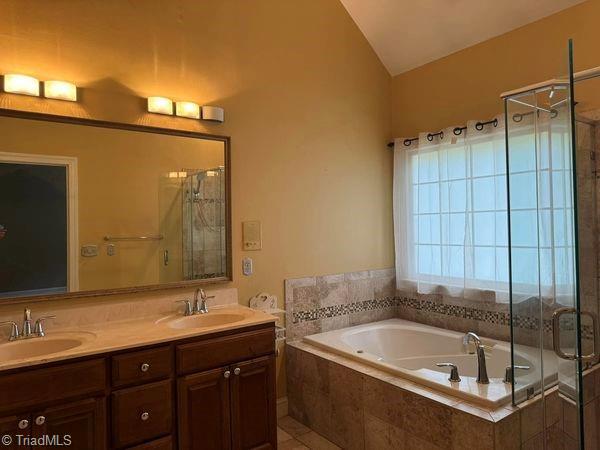 bathroom featuring a bath, a stall shower, lofted ceiling, and a sink