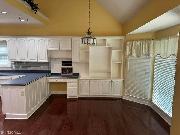 kitchen featuring dark countertops, open shelves, decorative light fixtures, lofted ceiling, and dark wood-style flooring