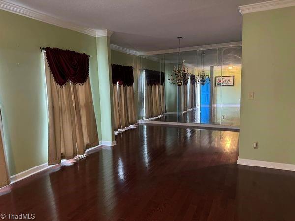 empty room featuring baseboards, wood finished floors, and ornamental molding