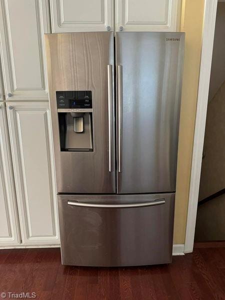 kitchen featuring dark wood finished floors, stainless steel fridge with ice dispenser, and white cabinets