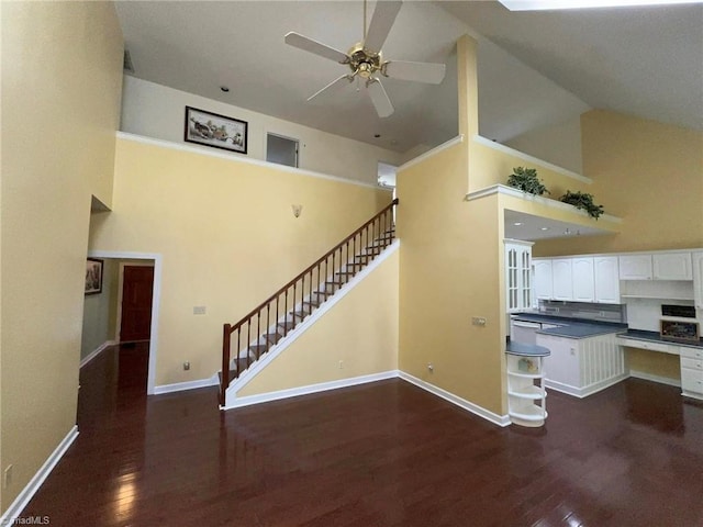 interior space featuring ceiling fan, baseboards, stairway, wood finished floors, and high vaulted ceiling