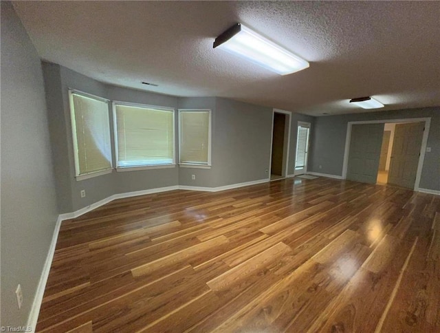 empty room with wood finished floors, baseboards, and a textured ceiling