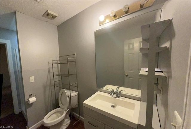 bathroom with vanity, baseboards, visible vents, a textured ceiling, and toilet