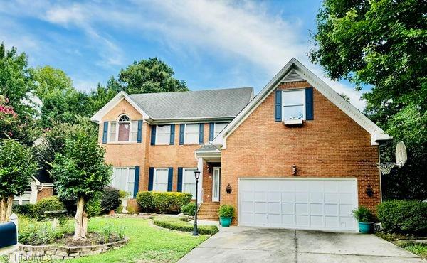 colonial home featuring brick siding, a front lawn, concrete driveway, and a garage