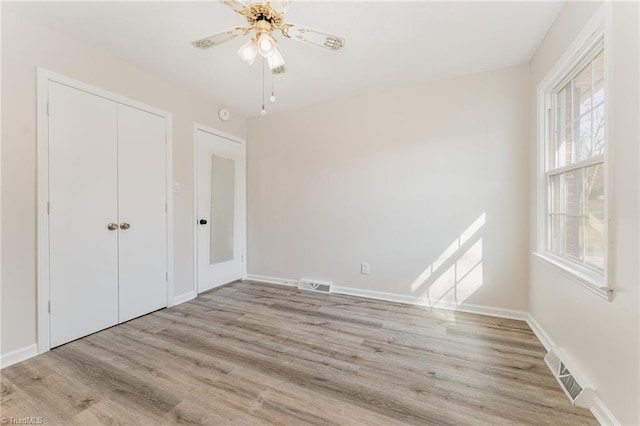 unfurnished bedroom featuring light wood finished floors, visible vents, baseboards, and a closet