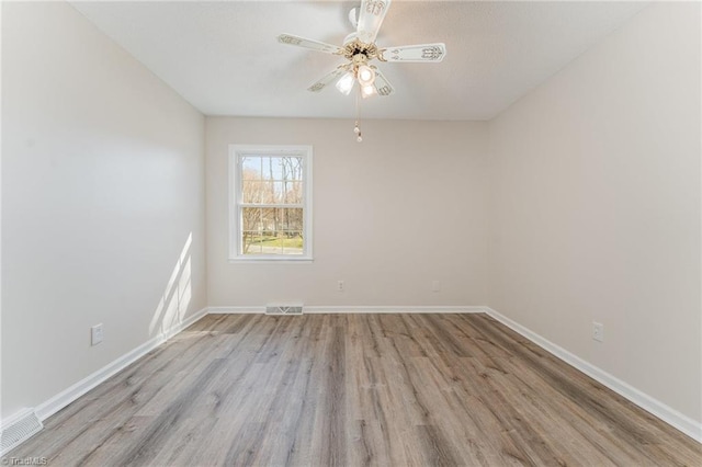 spare room featuring visible vents, baseboards, and wood finished floors