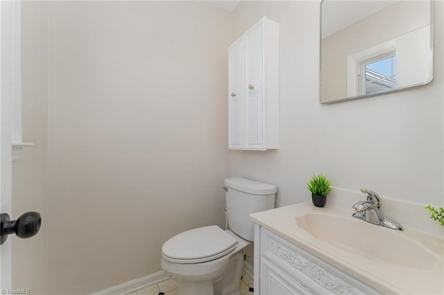 half bath with baseboards, toilet, and vanity