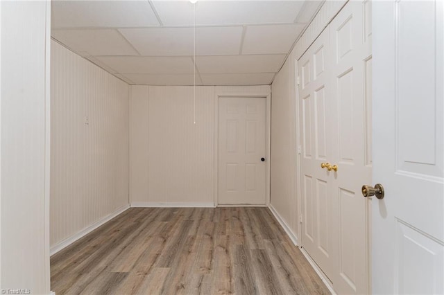 spare room with light wood finished floors, a paneled ceiling, and baseboards