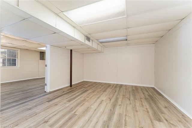 below grade area featuring wood finished floors, visible vents, a drop ceiling, and baseboards