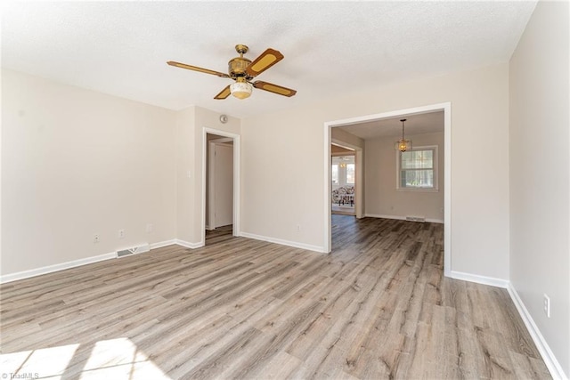 empty room featuring light wood-style flooring, a ceiling fan, baseboards, and a textured ceiling