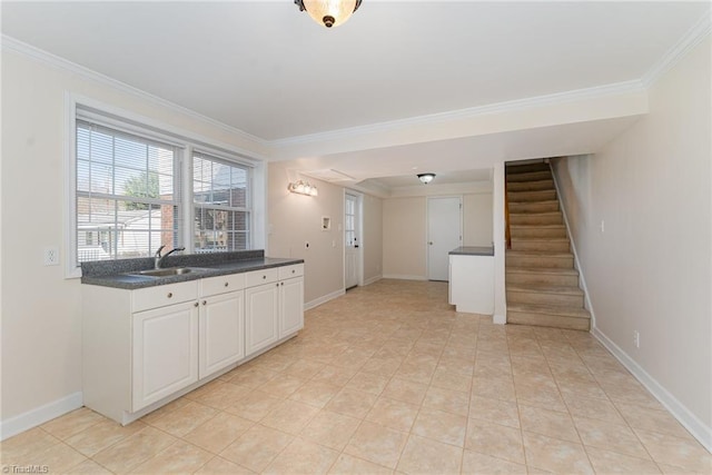 kitchen featuring a sink, baseboards, dark countertops, and crown molding