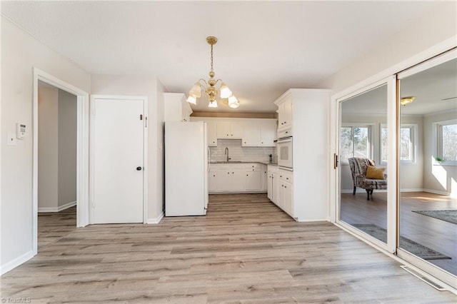 kitchen featuring tasteful backsplash, light wood-style floors, a notable chandelier, white cabinets, and white appliances