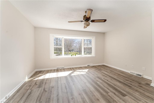 spare room with visible vents, baseboards, and wood finished floors