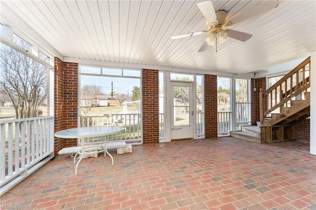 sunroom / solarium featuring a ceiling fan, wooden ceiling, and a healthy amount of sunlight