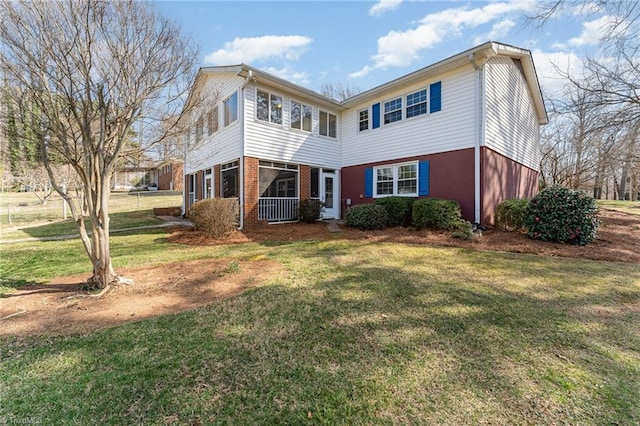 rear view of house with brick siding and a lawn