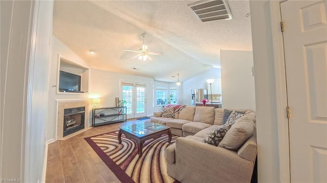 2309 Kasarda Dr, Greensboro, NC 27406 - living room with a ceiling fan, vaulted ceiling, a fireplace, light wood finished floors, and french doors