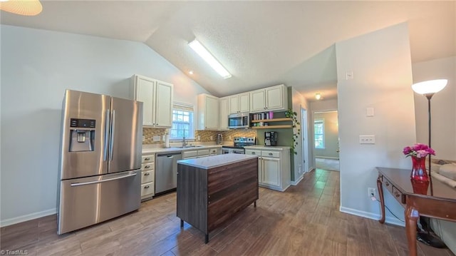 2309 Kasarda Dr, Greensboro, NC 27406 - kitchen featuring appliances with stainless steel finishes, lofted ceiling, wood finished floors, light countertops, and tasteful backsplash