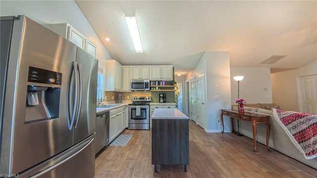 2309 Kasarda Dr, Greensboro, NC 27406 - kitchen featuring appliances with stainless steel finishes, a center island, light countertops, light wood-type flooring, and backsplash