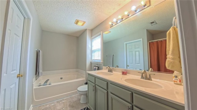2309 Kasarda Dr, Greensboro, NC 27406 - bathroom featuring a textured ceiling, a bath, double vanity, and toilet