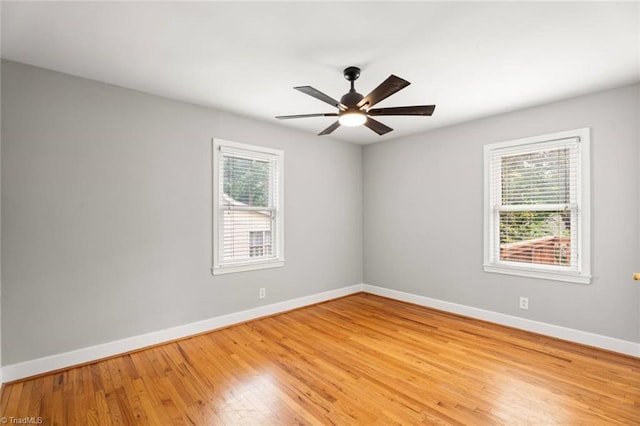 spare room featuring baseboards, light wood-style floors, and a ceiling fan