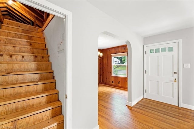 foyer entrance with arched walkways, stairway, light wood-type flooring, baseboards, and lofted ceiling