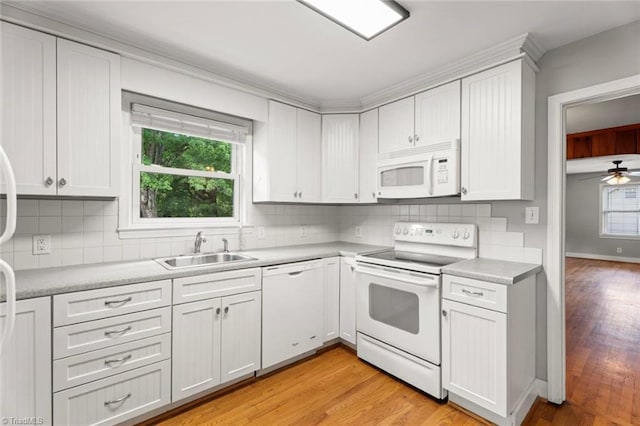 kitchen with white appliances, a sink, light countertops, light wood-type flooring, and backsplash