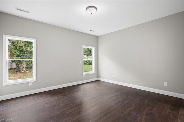 spare room featuring a wealth of natural light and dark hardwood / wood-style flooring